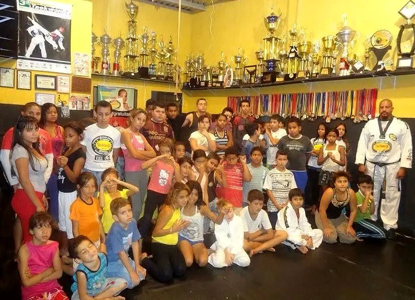 Grande grupo de crianças e educadores na sede do Projeto Raça